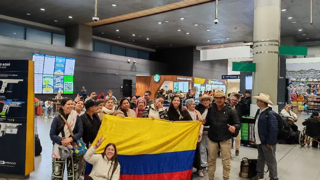 Grupo de viajeros con la bandera de Colombia en el aeropuerto