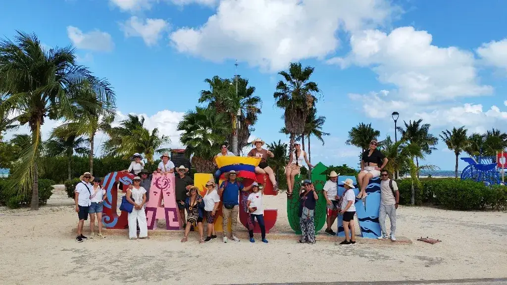 Grupo de viajeros en el letrero de Cancún con la bandera de Colombia