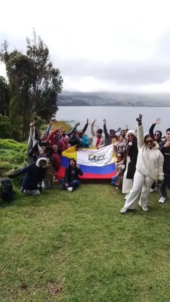 Viajeros sonrientes con la bandera de Colombia en un paisaje de laguna